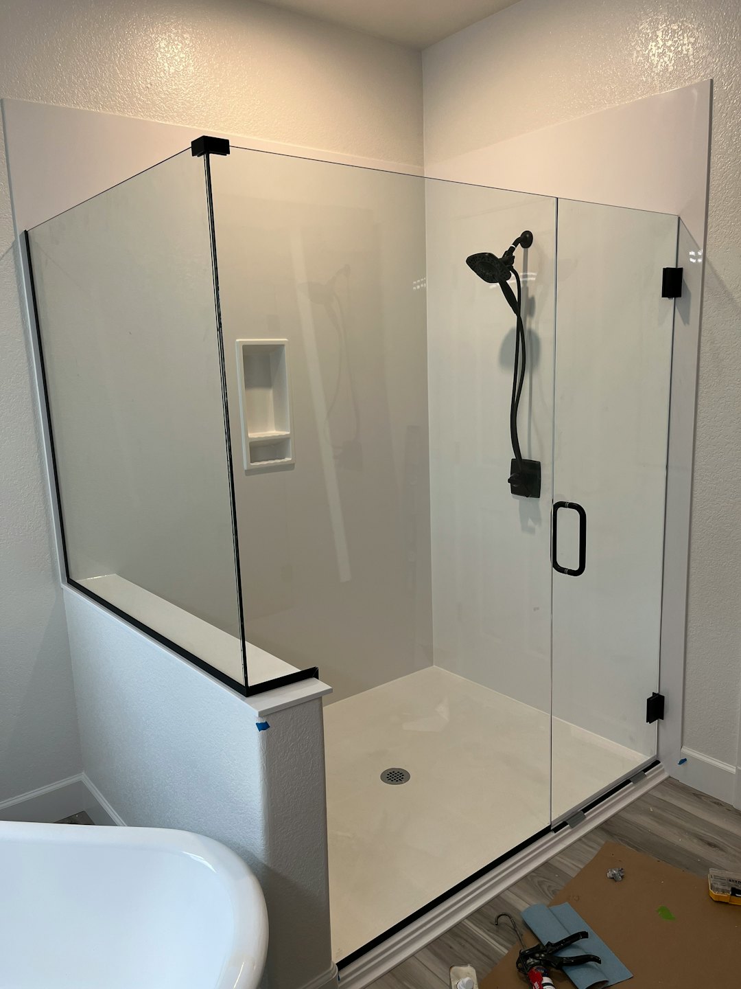 Modern walk-in shower with black fixtures and glass panels.
