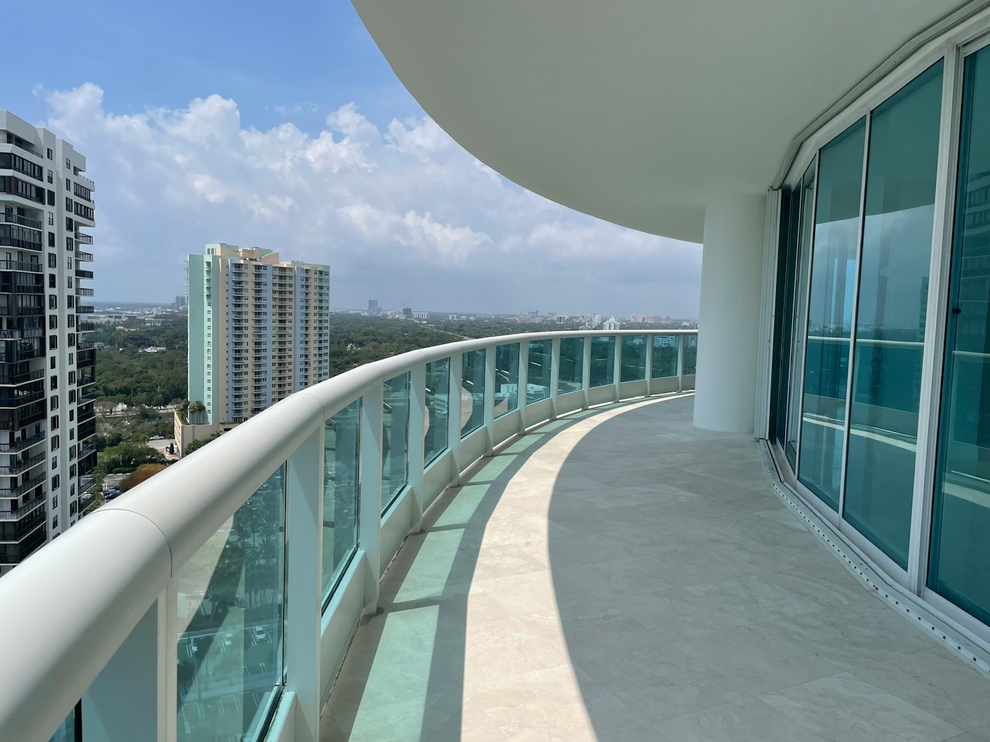 Modern high-rise balcony overlooking a sprawling urban city skyline.