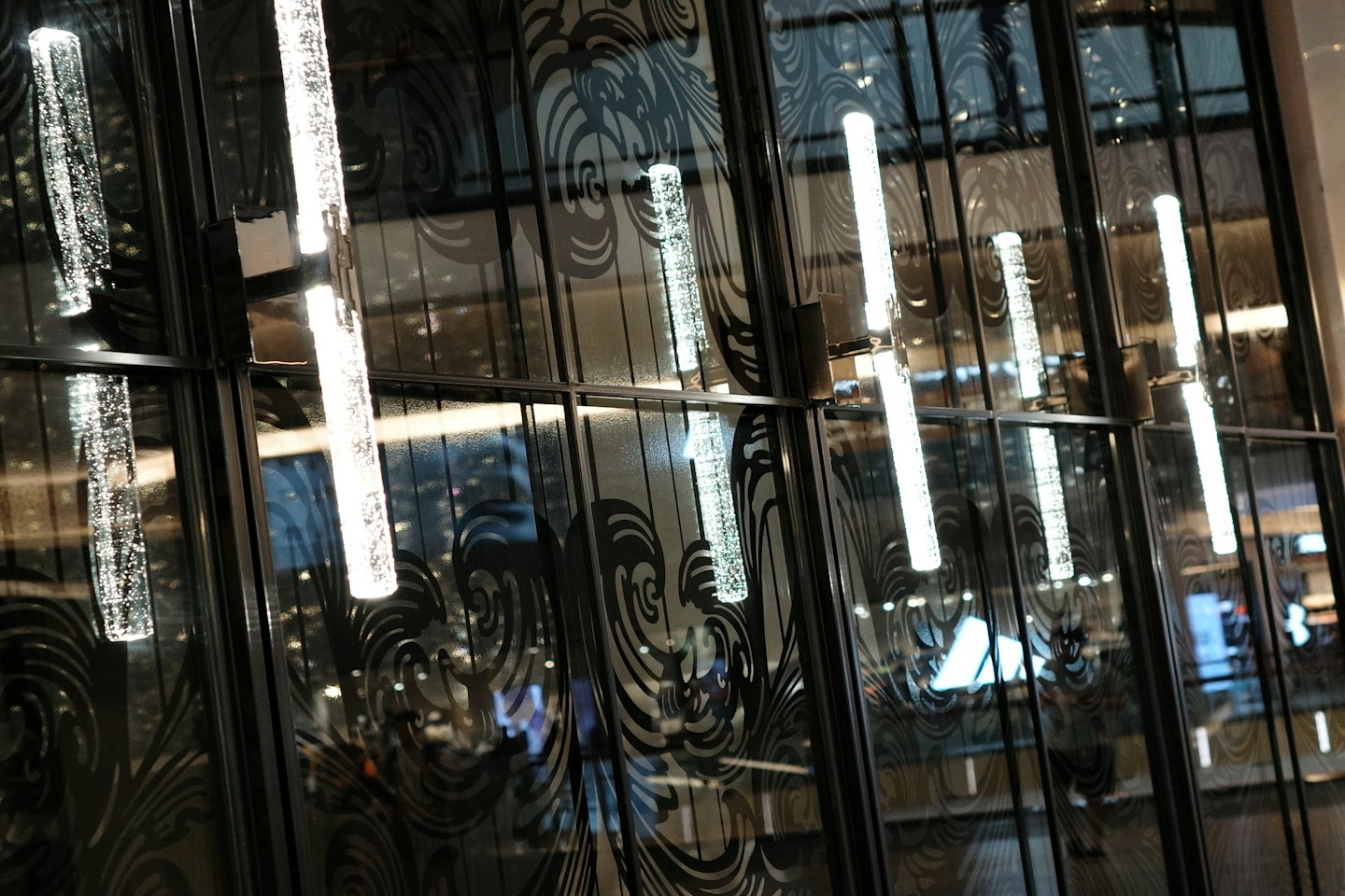 Dark glass wall panels with swirling patterns and cylindrical lights.
