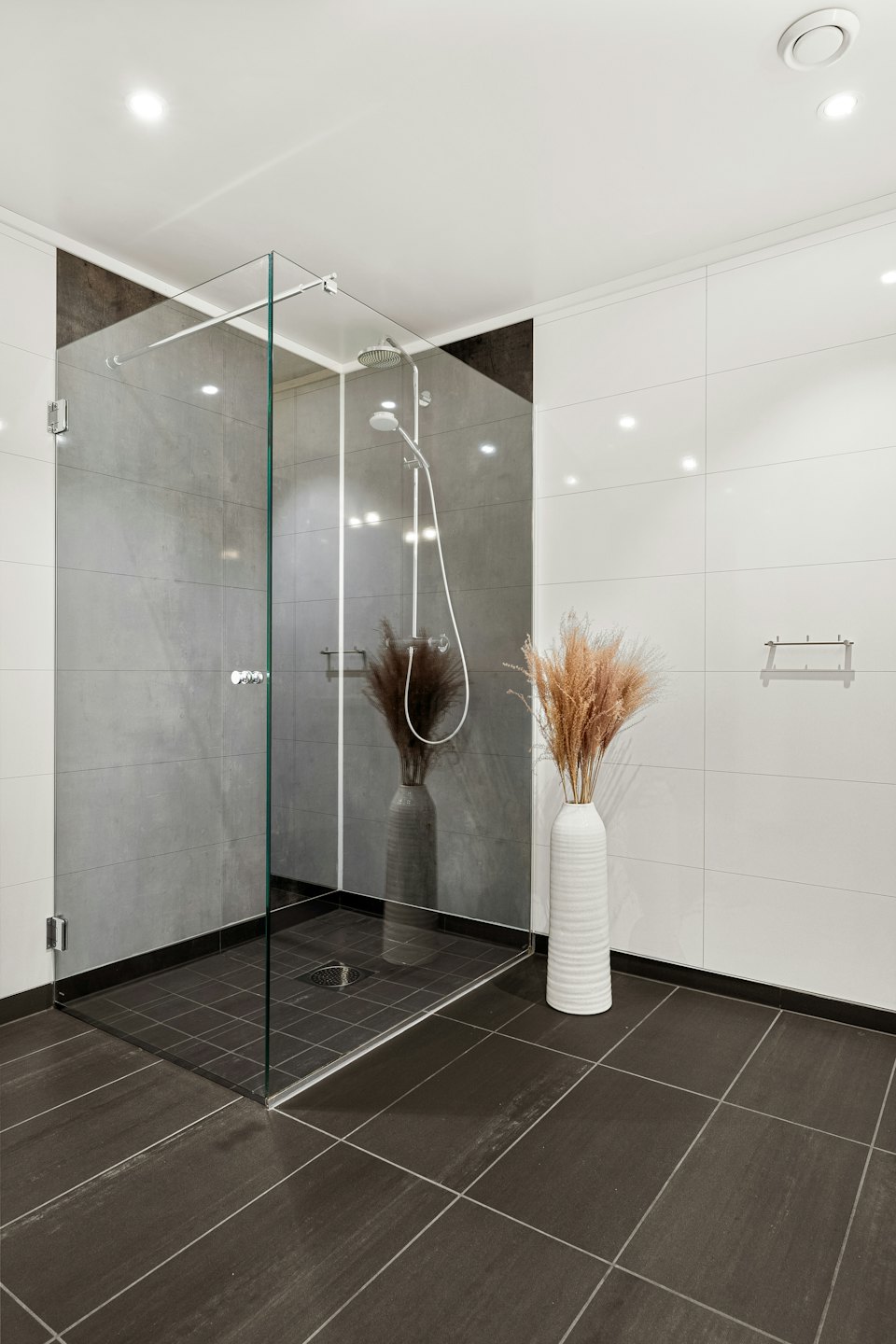 Modern bathroom featuring a glass shower and decorative floor vase.
